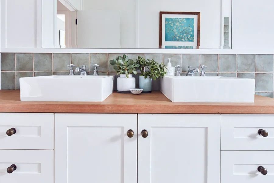 White Bathroom Vanity with Two Vessel Sinks and Small Potted Plants on A Wood Countertop — Fineworx Joinery in Warnervale, NSW