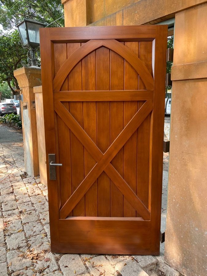 Wooden Front Gate with An Arched Cross Braced Design Set in A Stone Walkway — Fineworx Joinery in Warnervale, NSW