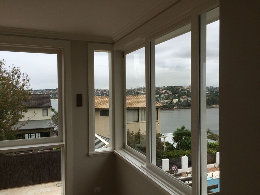 White House Corner with Bay Windows and Grey Roof Against an Overcast Sky — Fineworx Joinery in Warnervale, NSW