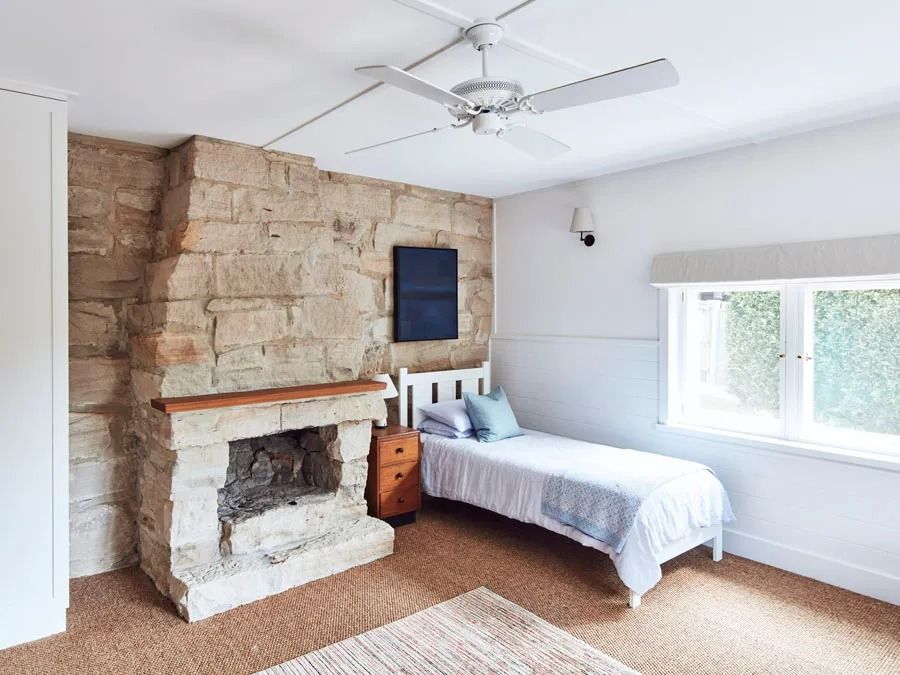 Bright Bedroom with Stone Fireplace then White Bed and Large Window — Fineworx Joinery in Warnervale, NSW