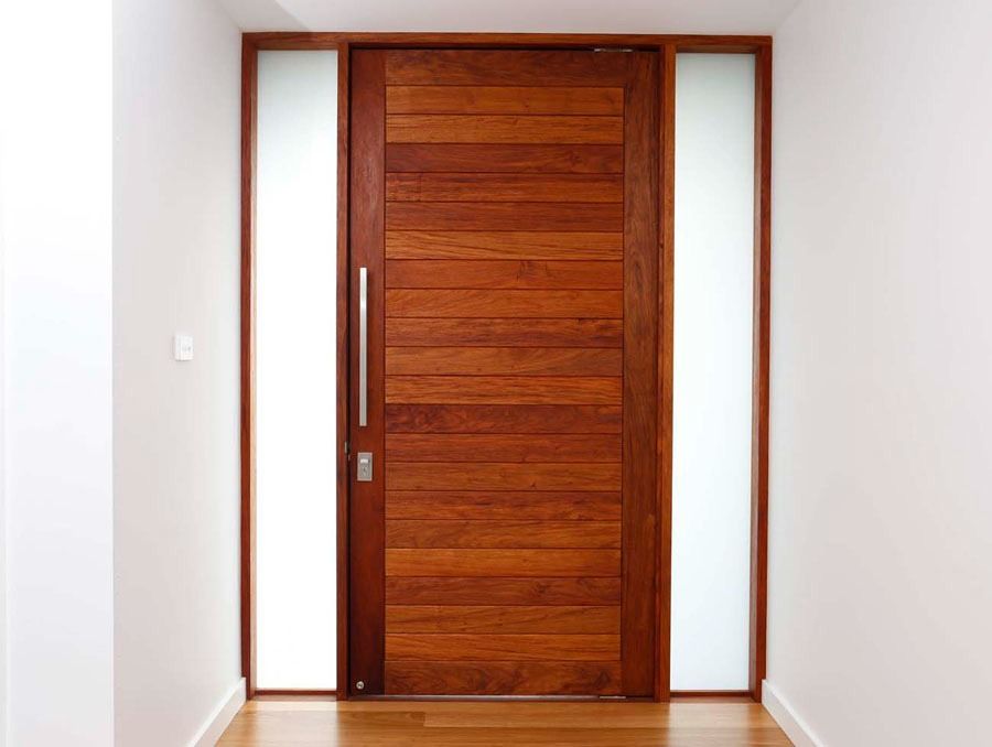 Modern Wooden Front Door with Frosted Glass Side Panels in A White Hallway — Fineworx Joinery in Warnervale, NSW