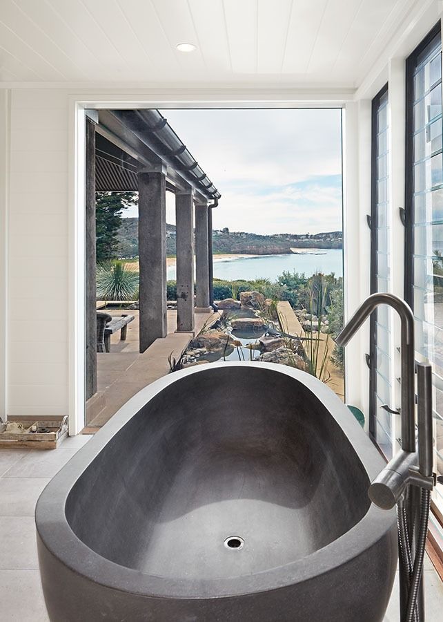 Modern bathroom with freestanding tub overlooking a waterfront patio and distant view — Fineworx Joinery in Warnervale, NSW