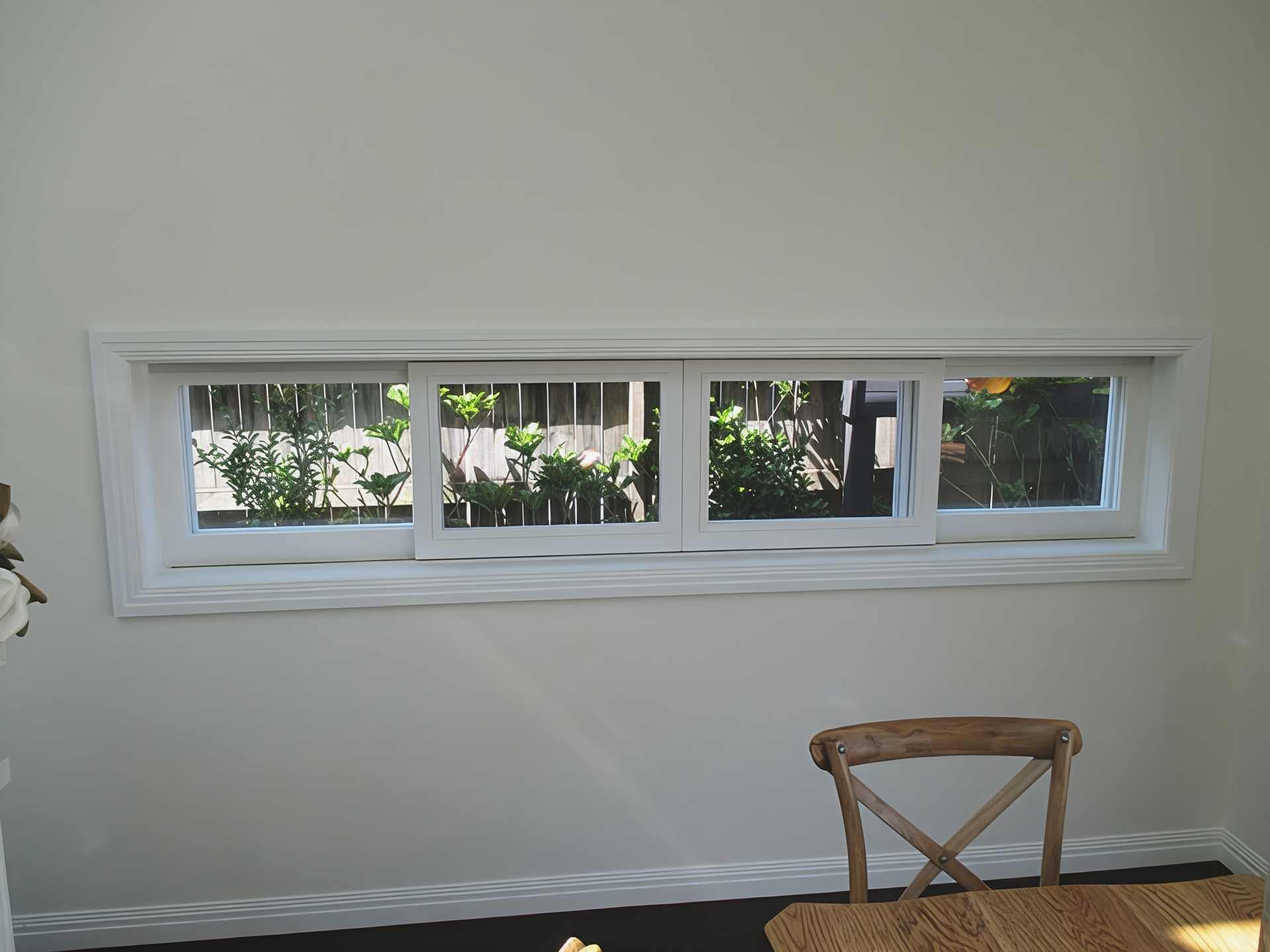 White Wall with A Long Horizontal Window and A Wooden Chair Beneath It — Fineworx Joinery in Nambucca Heads, NSW