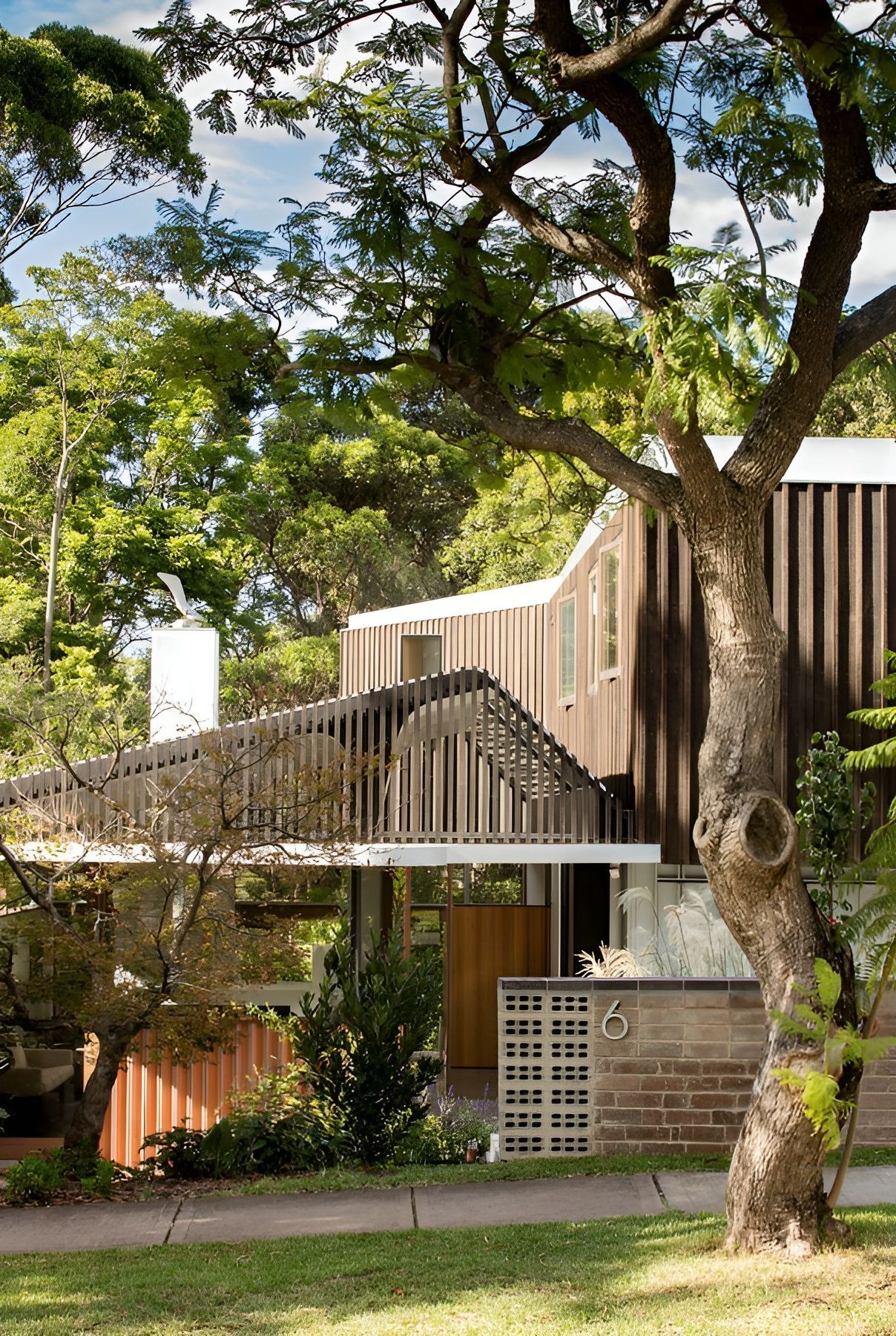 Tree-Shaded Modern House with Slatted Balcony and Brick Wall Behind a Front Lawn — Fineworx Joinery in Nambucca Heads, NSW