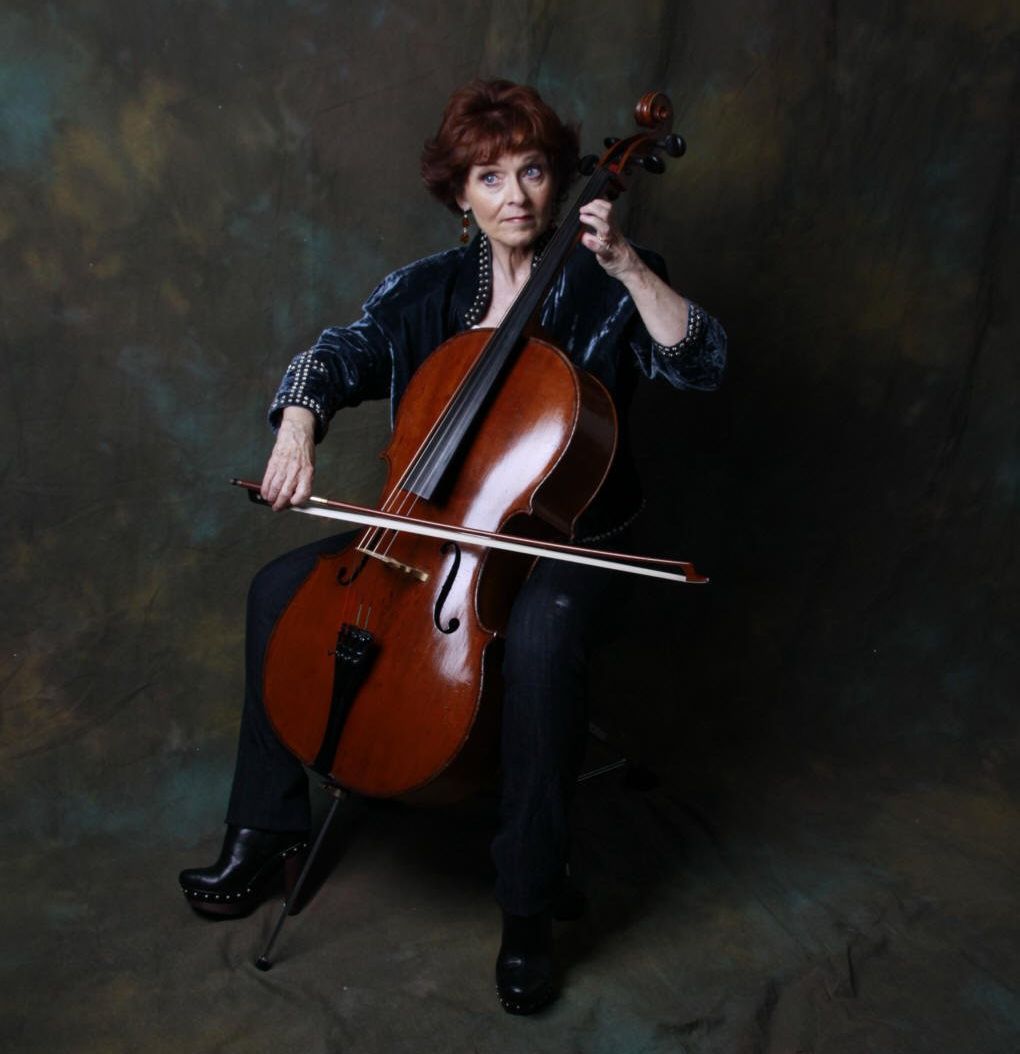 A woman is sitting on a chair playing a cello