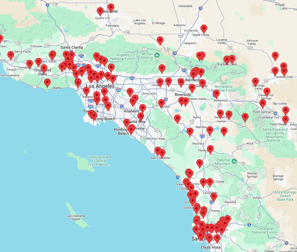 Map with many red location pins clustered along a coastline and inland roads.