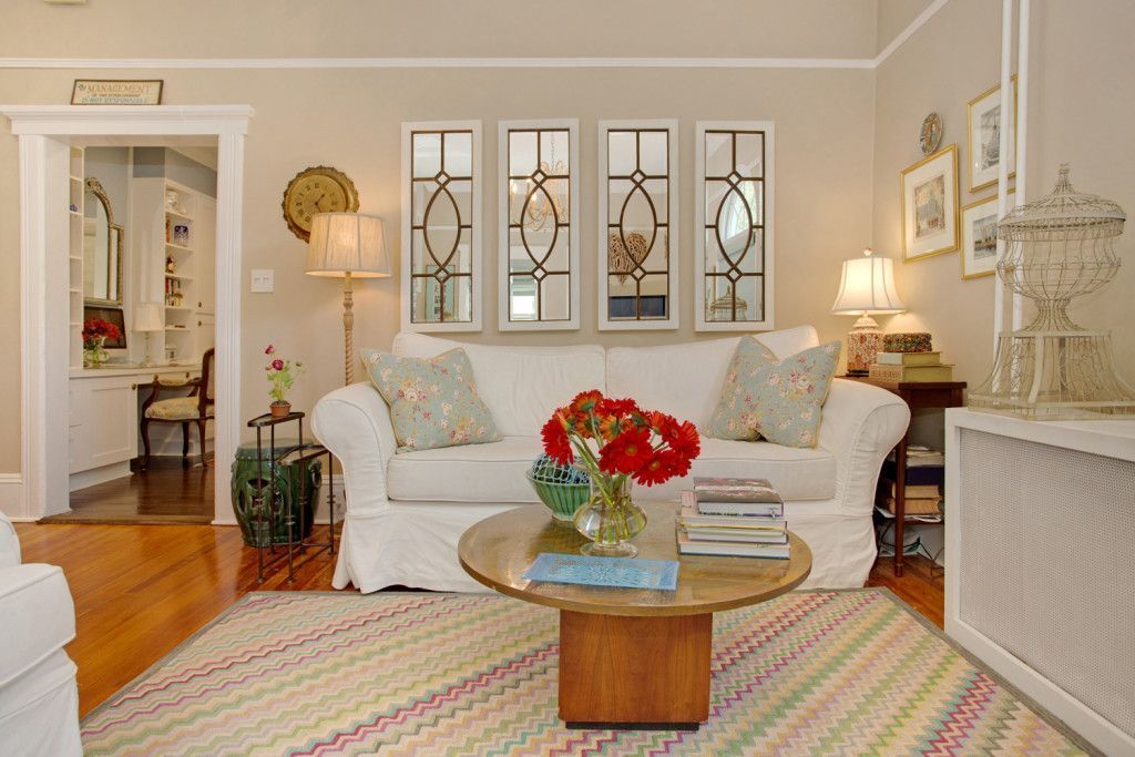 There's a couch and some windows. There's a table with some flowers on it or something.
