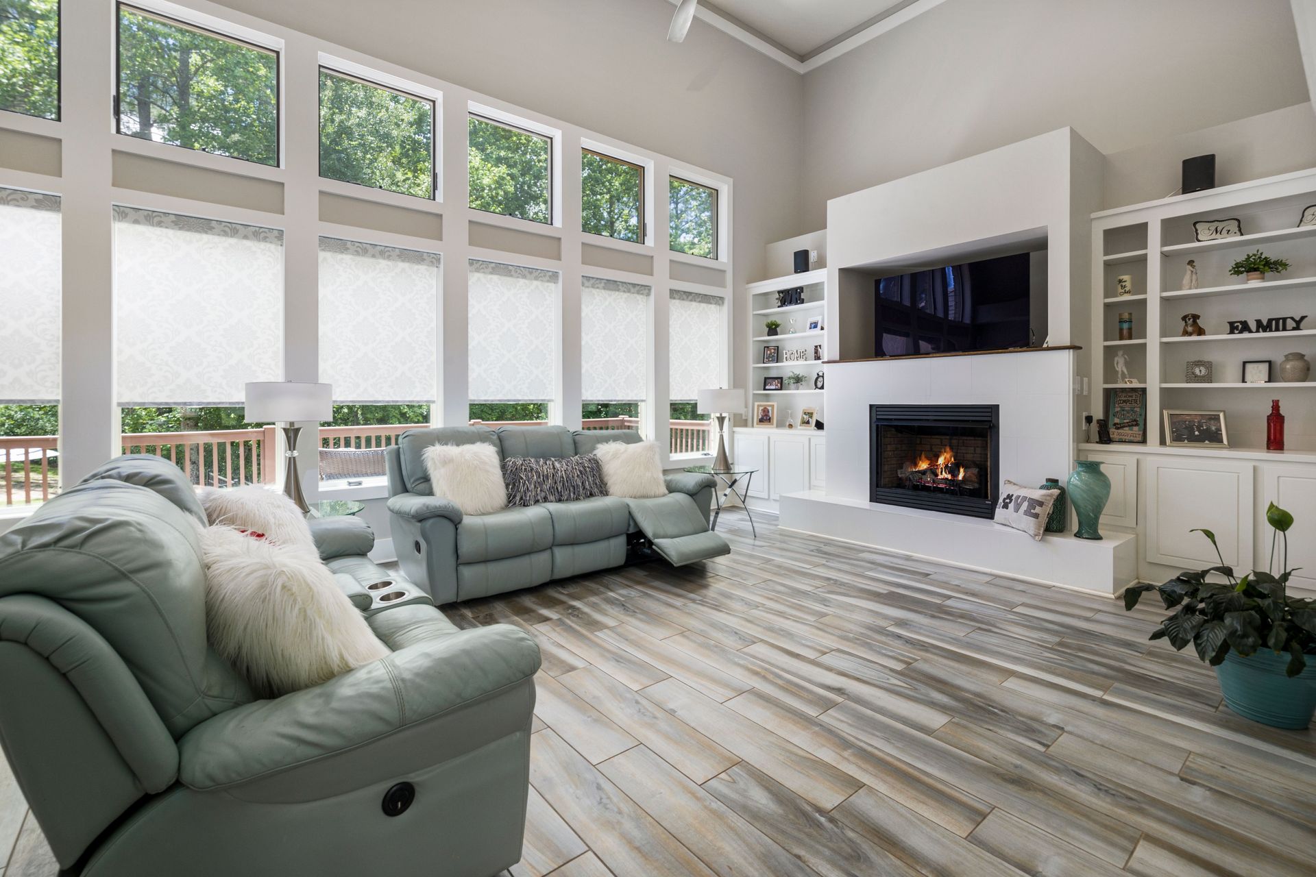 Bright living room with tall windows, mint sofas, and a white fireplace with built-in shelves