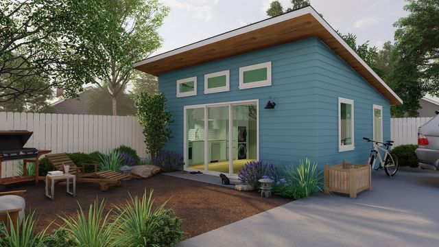 Small blue backyard office with patio, sliding glass doors, and outdoor seating in a landscaped yard