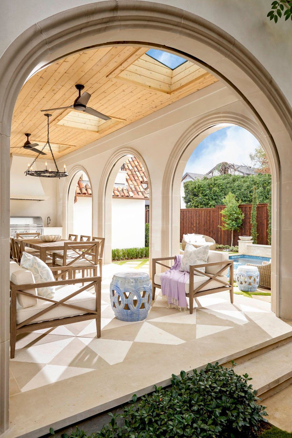 A porch with arches and a pool in the backyard.