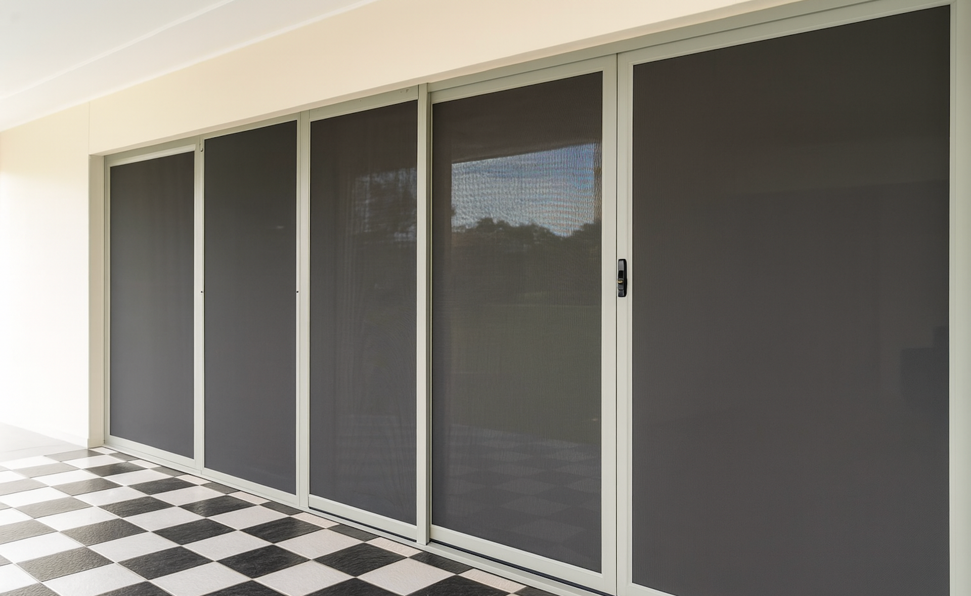 Row of dark window shades along a beige wall — Screen Factory In Byron Bay, NSW