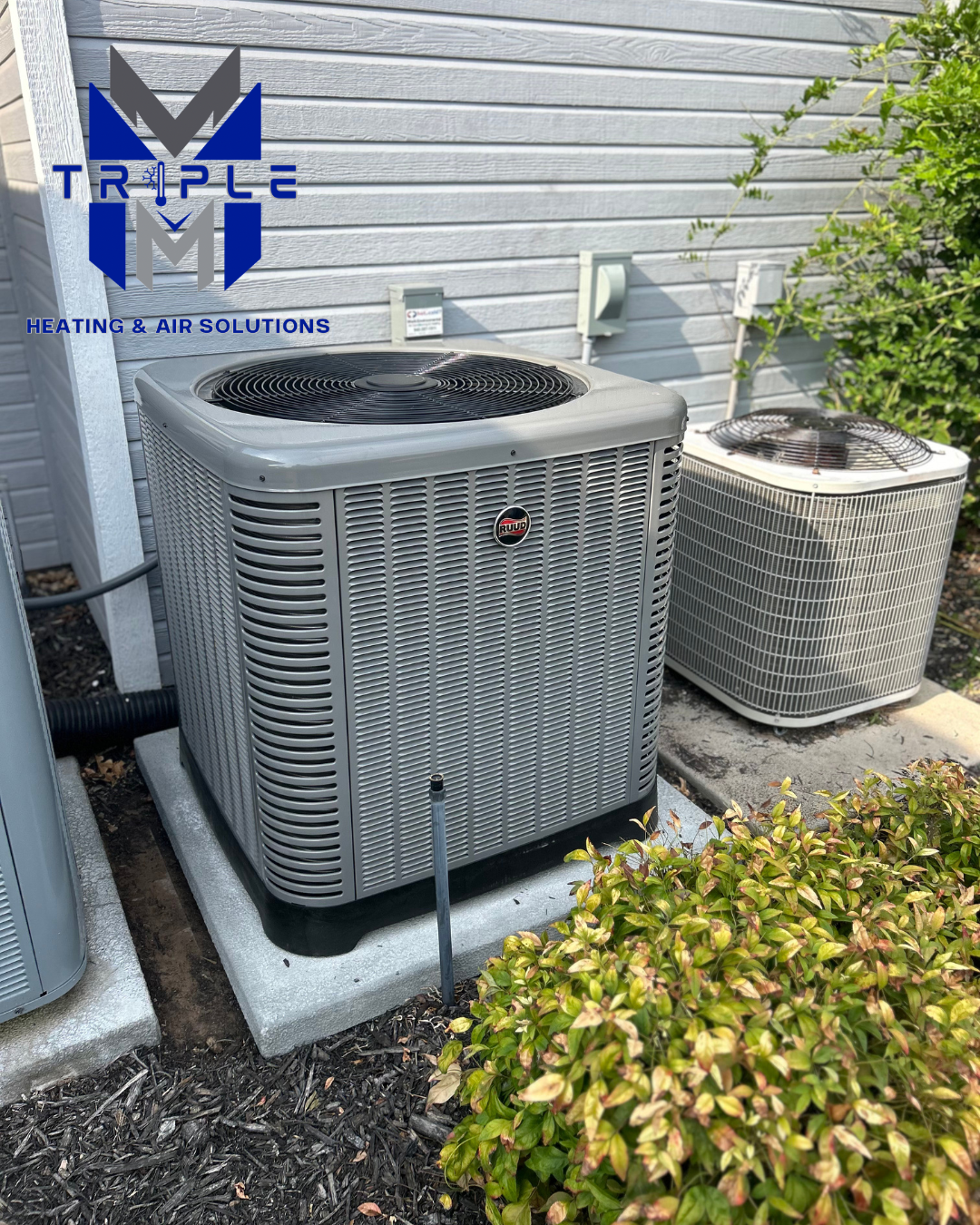 Outdoor air conditioning units on concrete pads beside a building with Triple M logo.