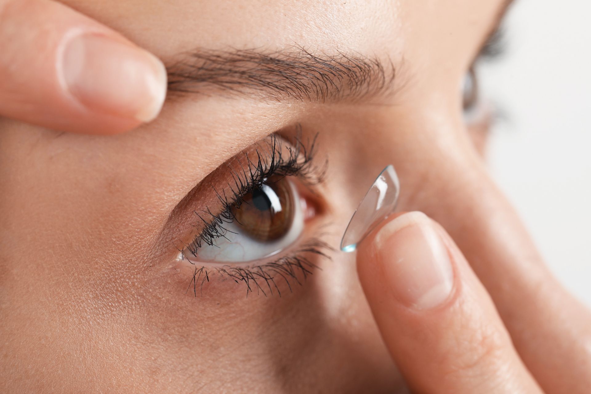 Close-up of a person carefully inserting a soft contact lens into their eye.