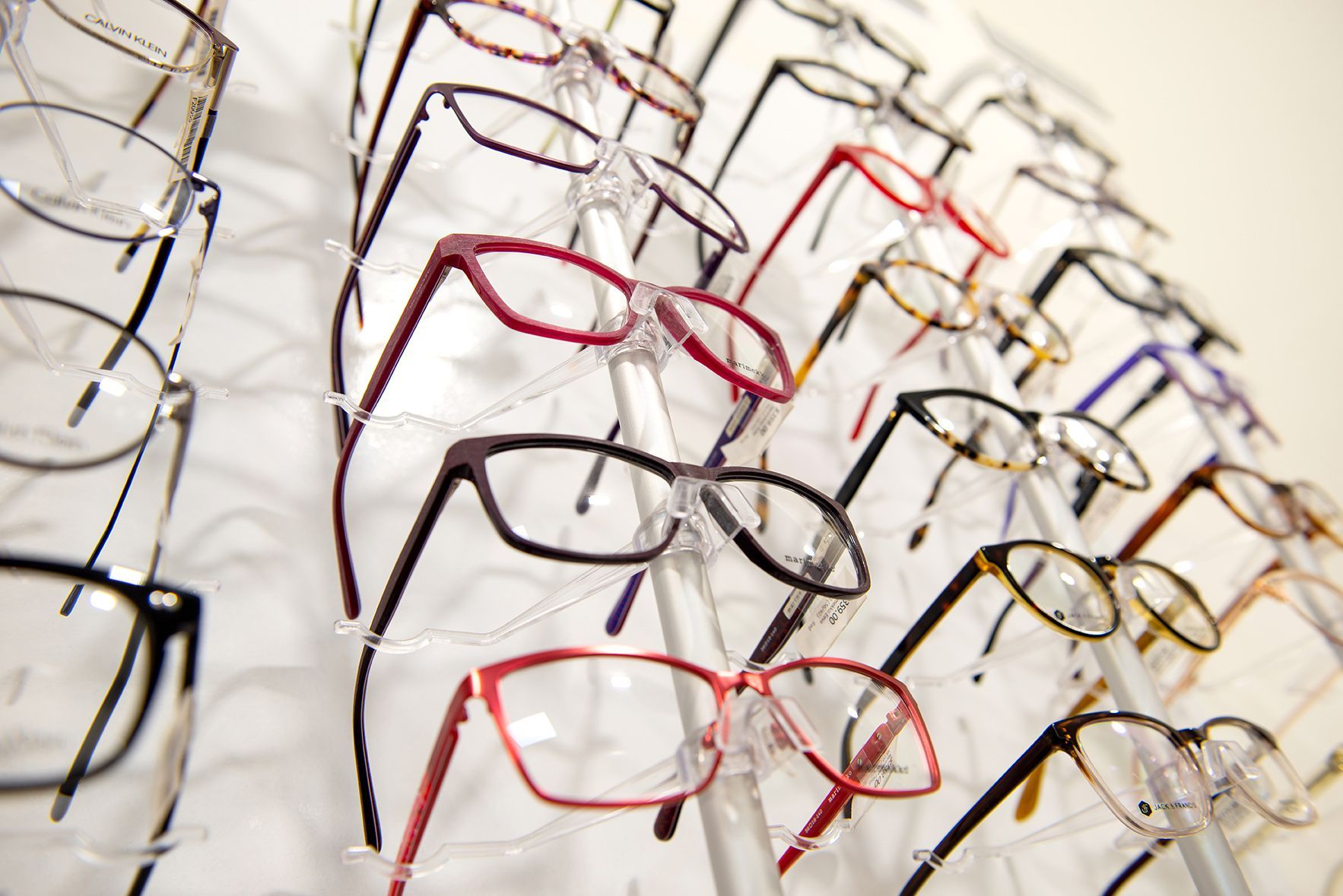 Eyeglass frames displayed on a white wall in an optician's office; various colors and styles.