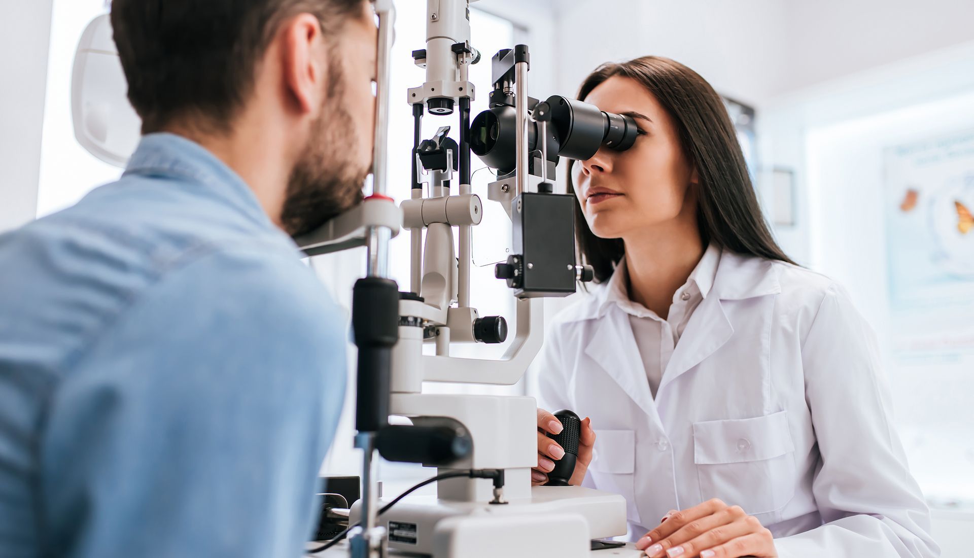 Optometrist examining a patient's eyes with a slit lamp in a clinic.