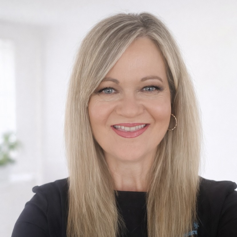 Smiling woman with long blonde hair in a black top against a light background