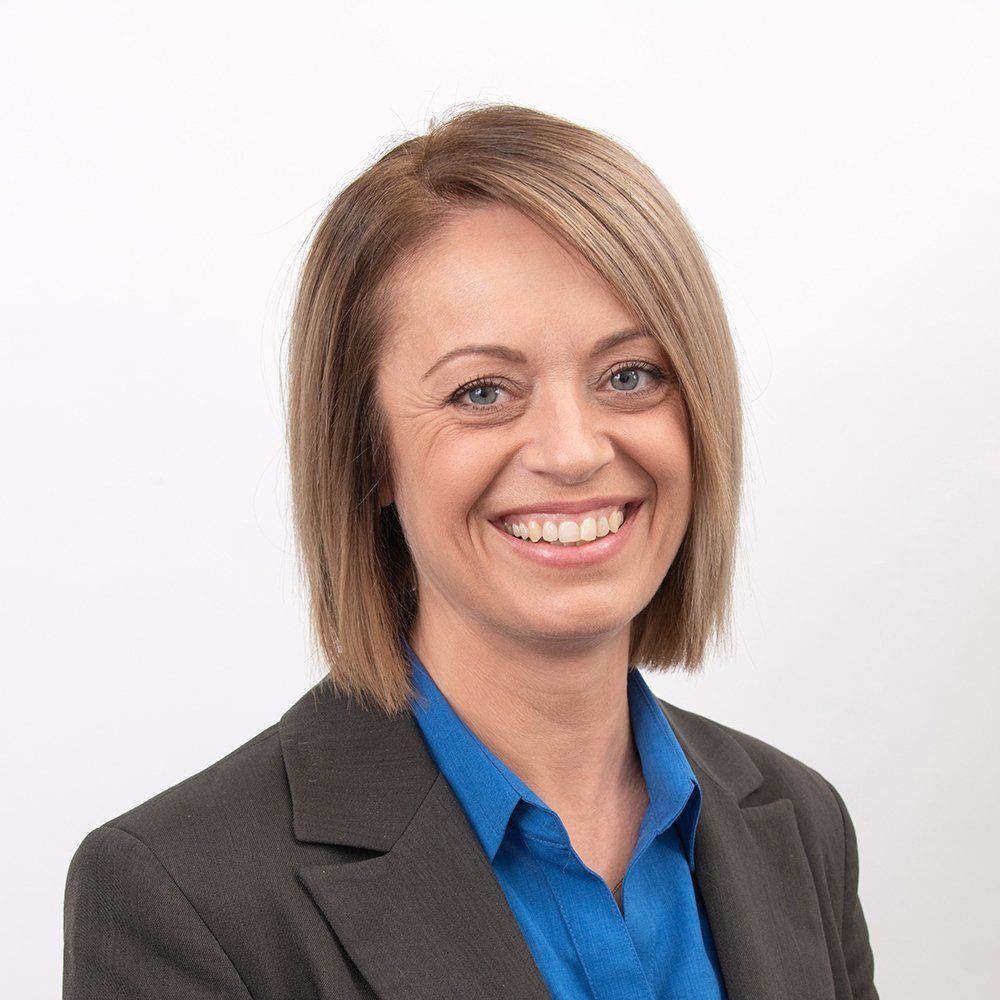 Smiling professional in a gray blazer and blue shirt on a white background