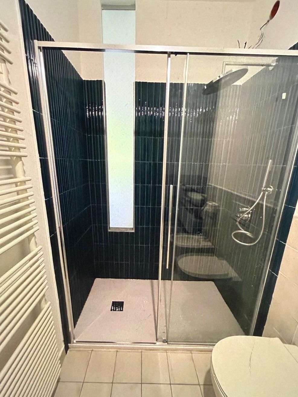 Bagno moderno con box doccia in vetro, piastrelle bianche e WC in primo piano.