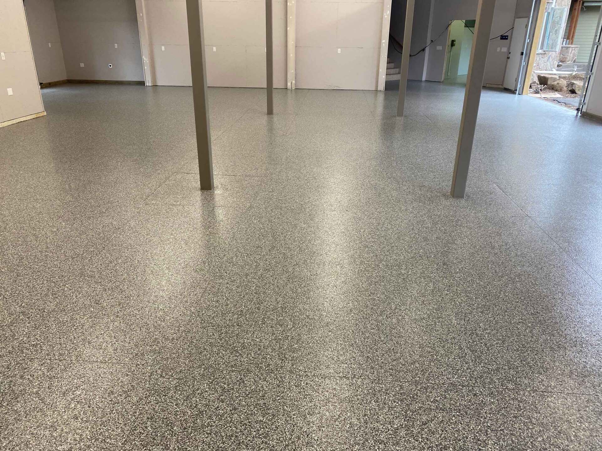 Gray speckled epoxy flooring in a room with support beams.