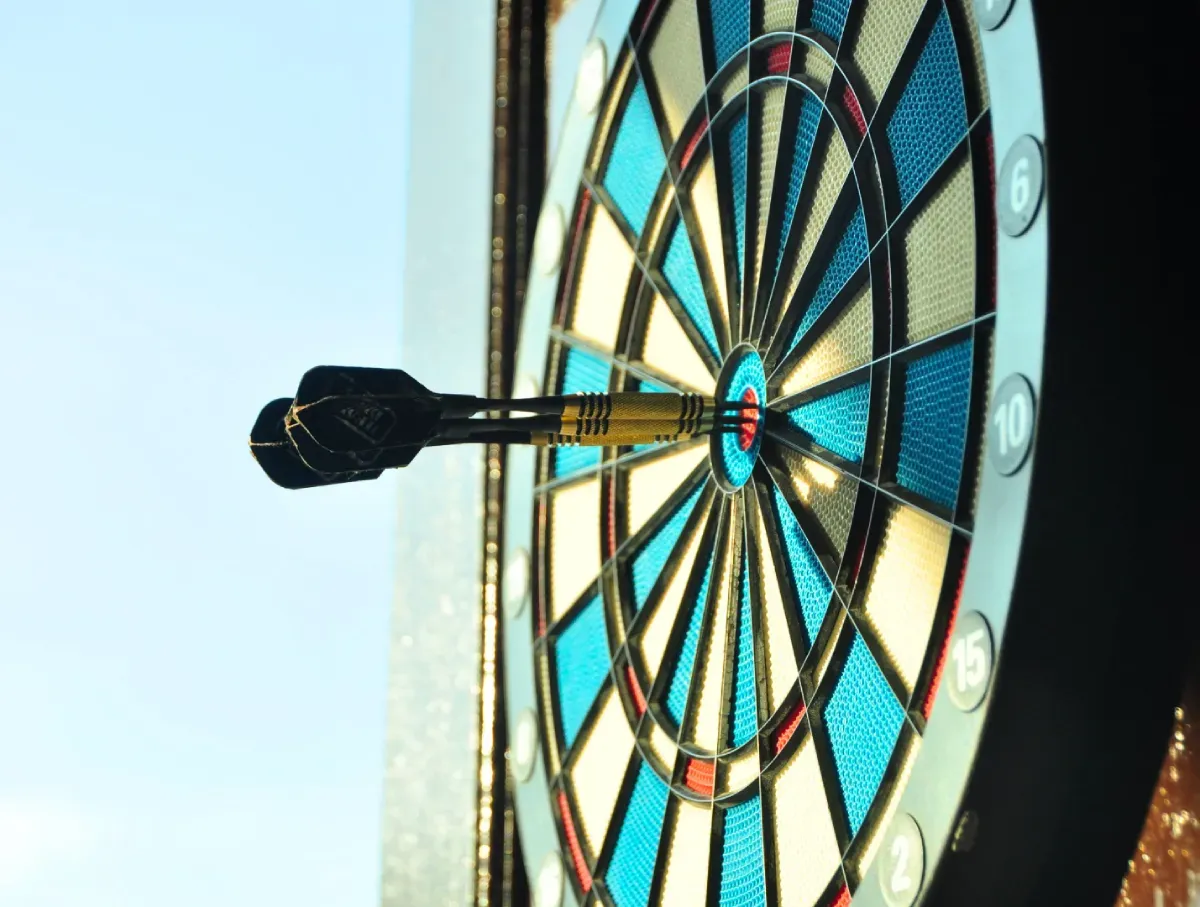 Close-up  photo of 3 darts on the bullseye of a blue and white dartboard.