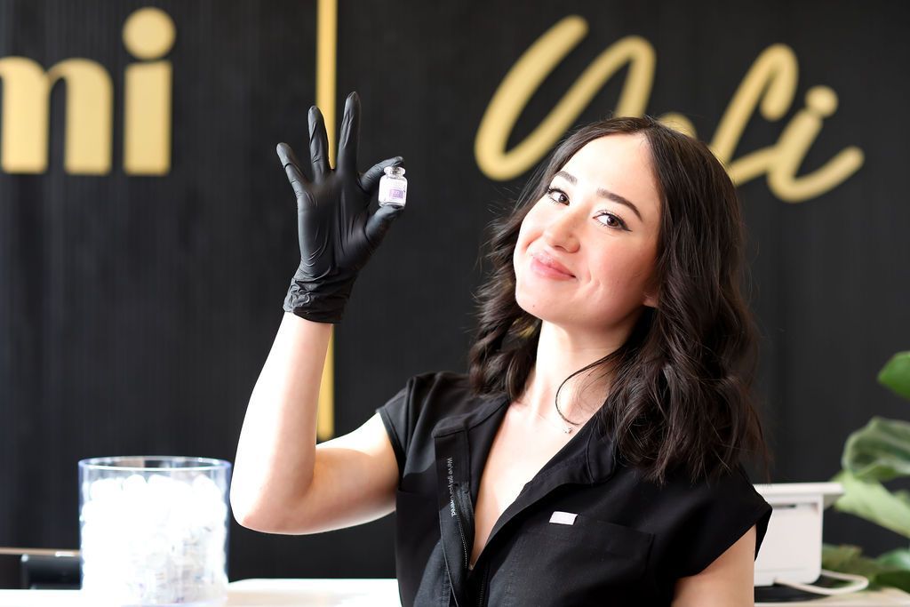 A woman wearing a black shirt and black gloves is holding something in her hand.