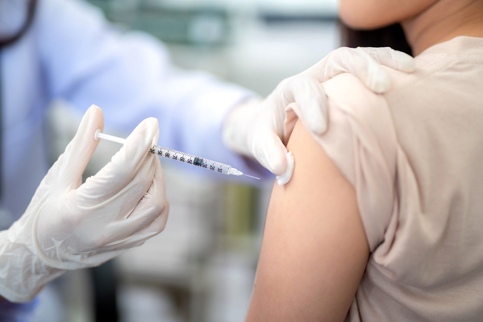 Gloved healthcare worker giving an injection in a patient’s upper arm