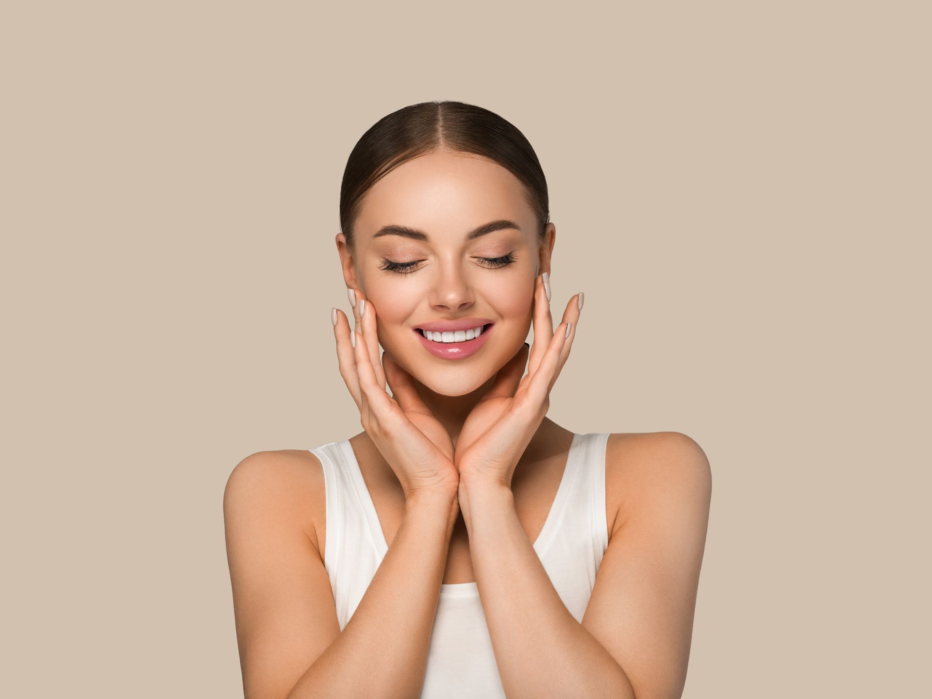 Smiling woman with hands on her cheeks against a beige background