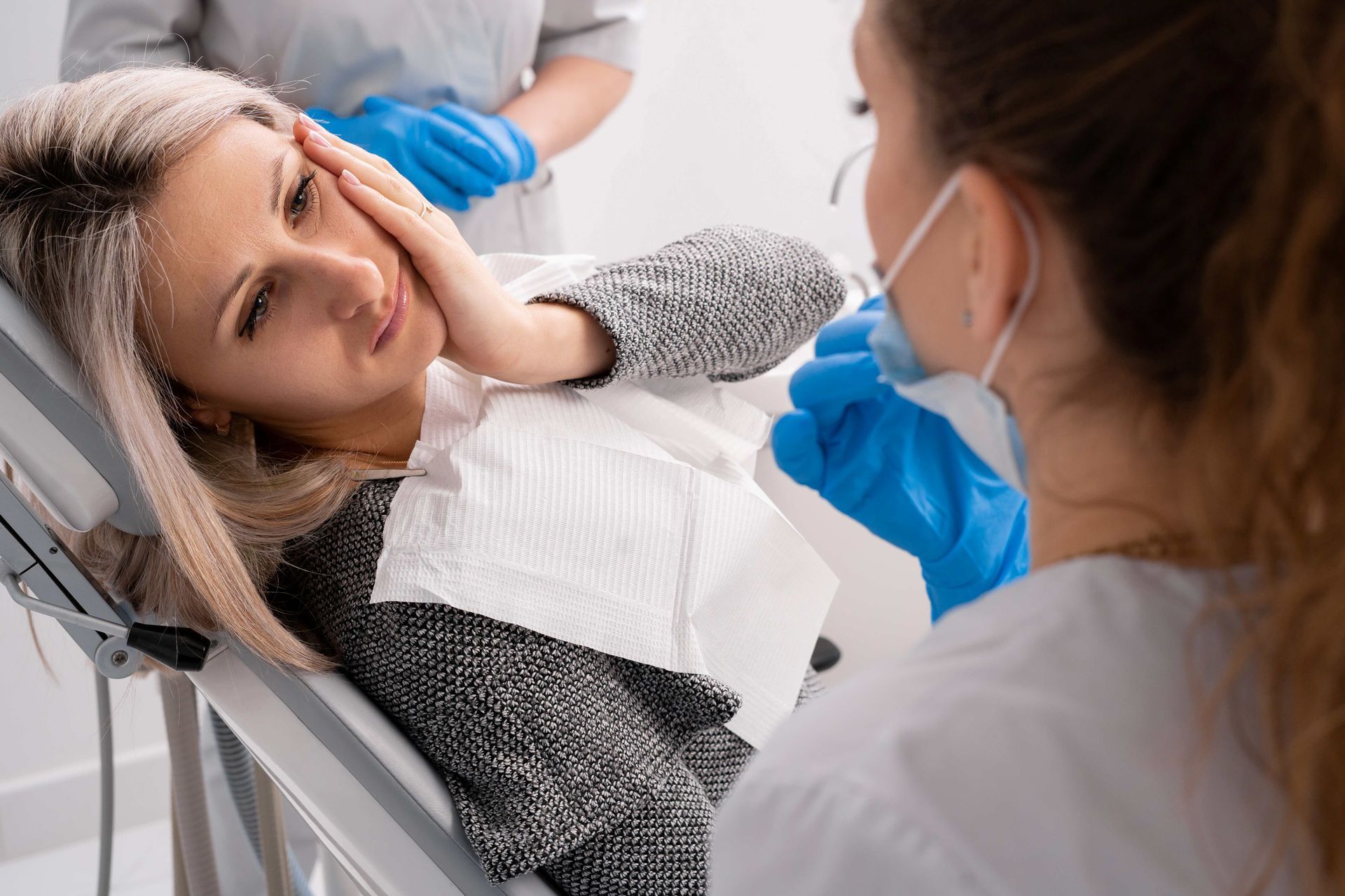 Patient holding cheek in pain during emergency dental consultation. Patient holding cheek in pain during emergency dental consultation.