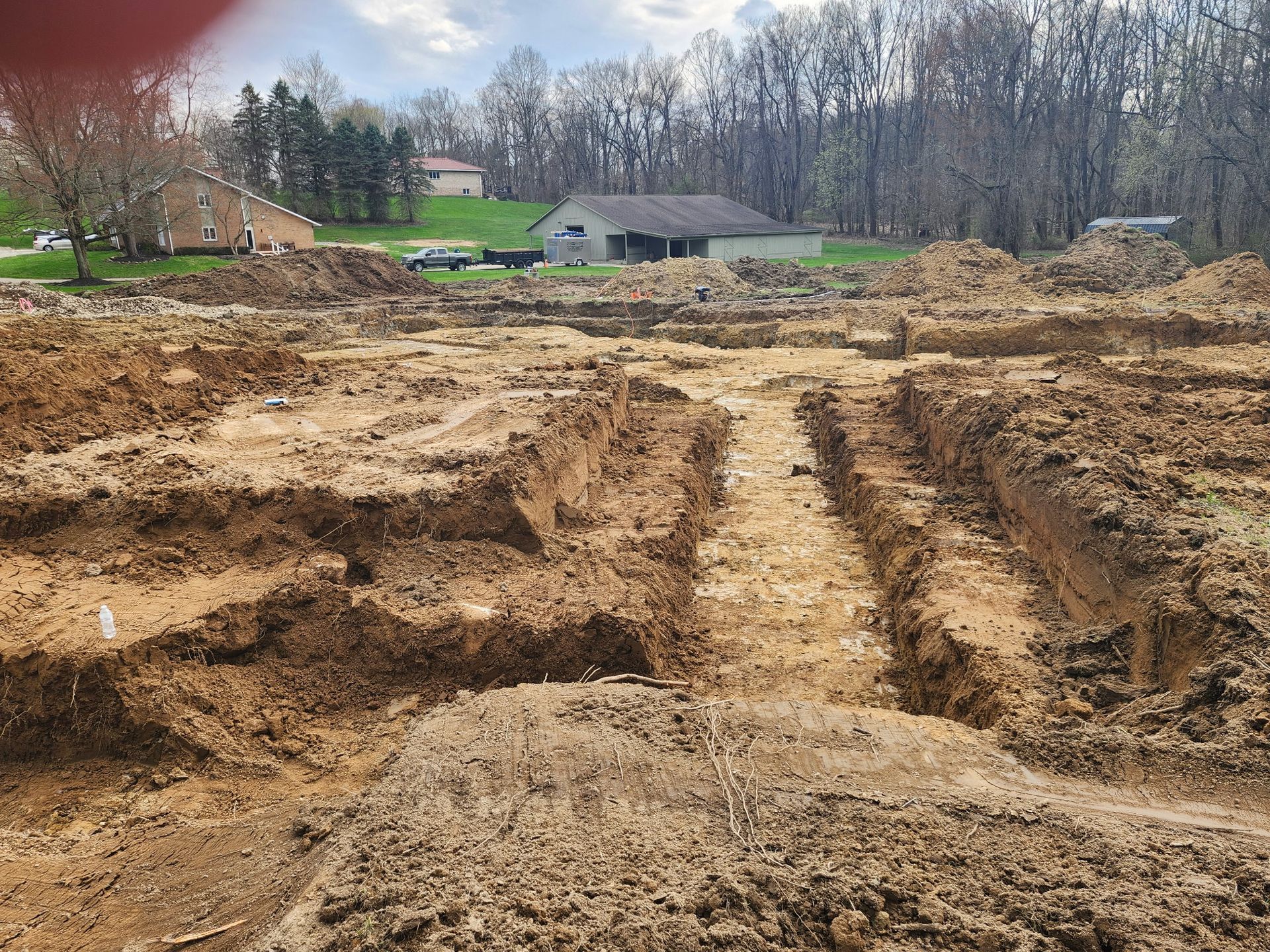 A construction site with a lot of dirt and a house in the background.