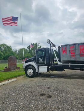 A dump truck is parked in front of an american flag