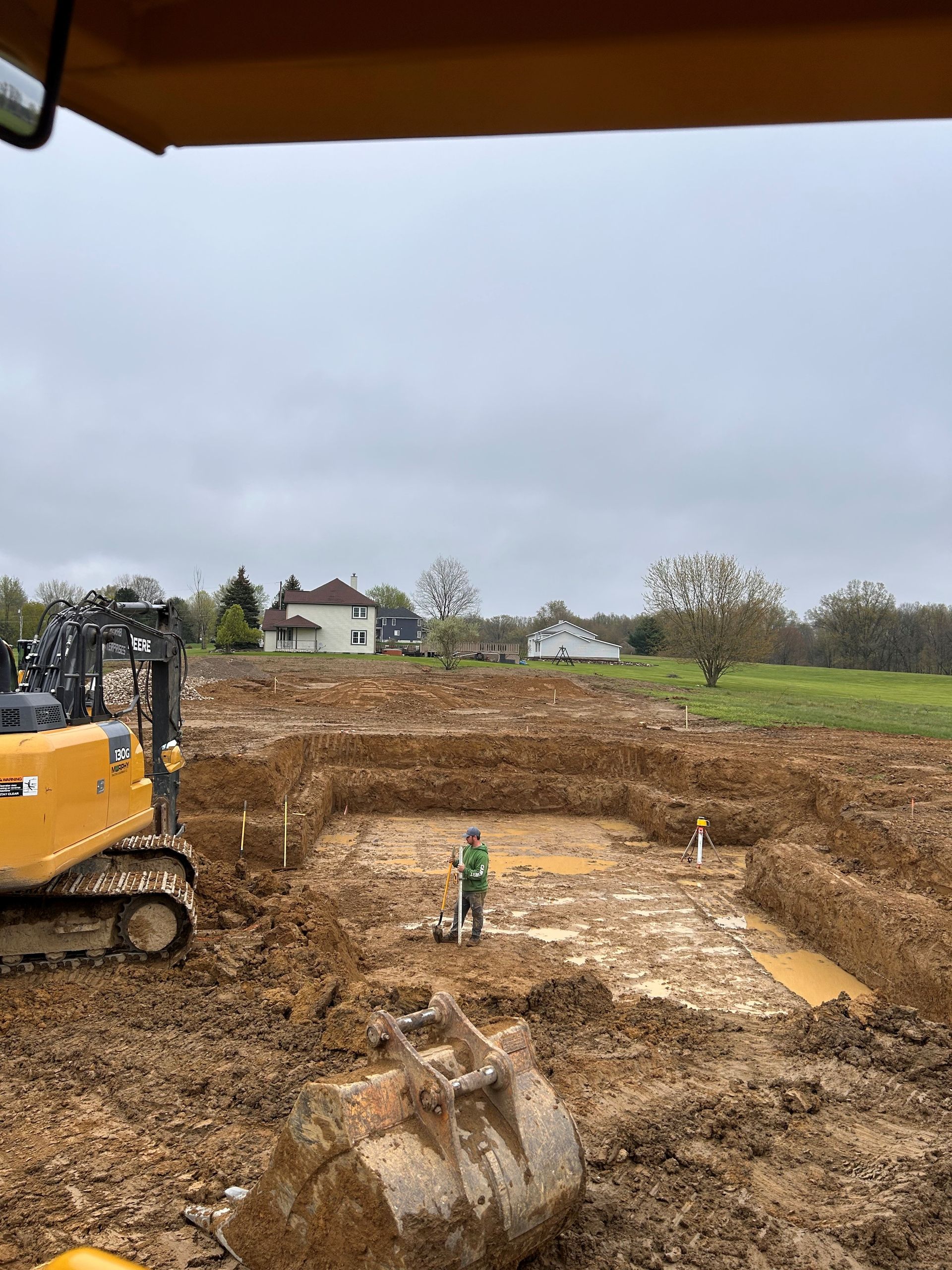 A construction site with a bulldozer and a man standing in the dirt