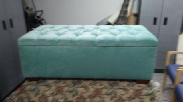 A blue ottoman is sitting on a rug in a room.