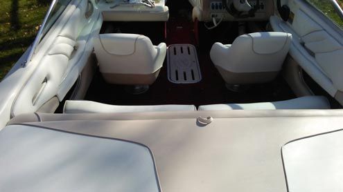 The back of a boat with white seats and a steering wheel