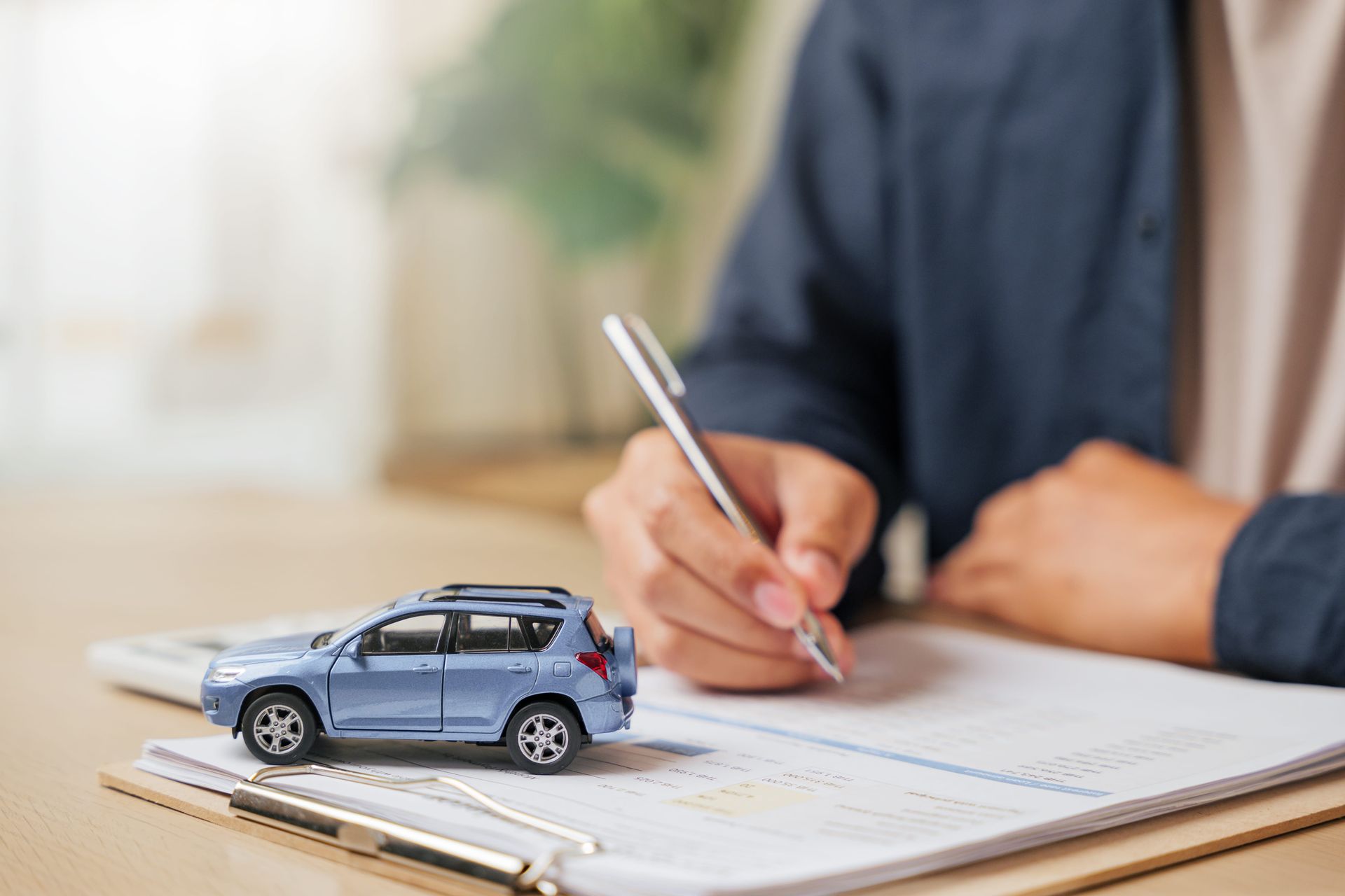 Mini SUV model on paperwork while a person writes on a clipboard at a desk