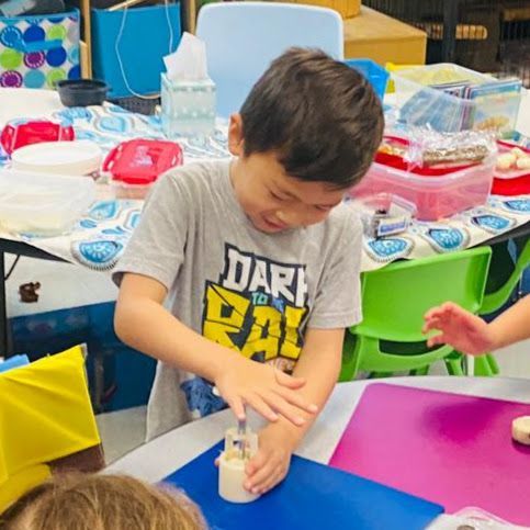 Child using a mortar and pestle at a colorful classroom science table