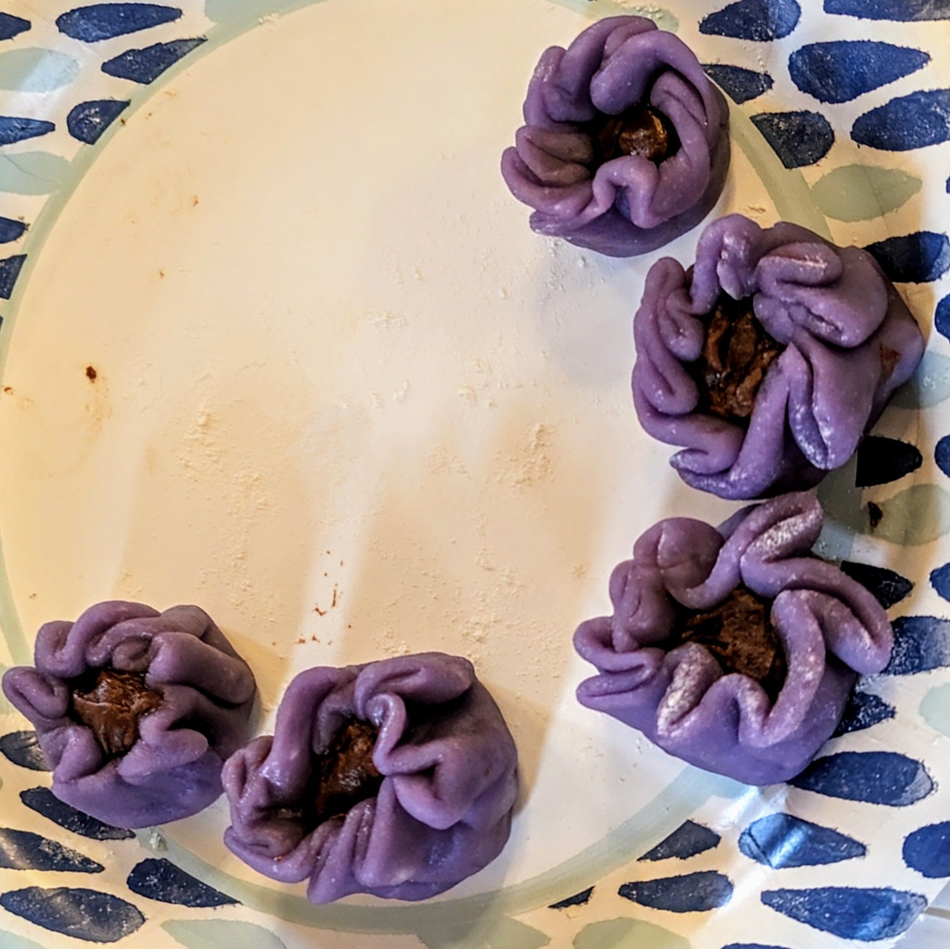 Five purple flower-shaped pastries arranged on a white plate.