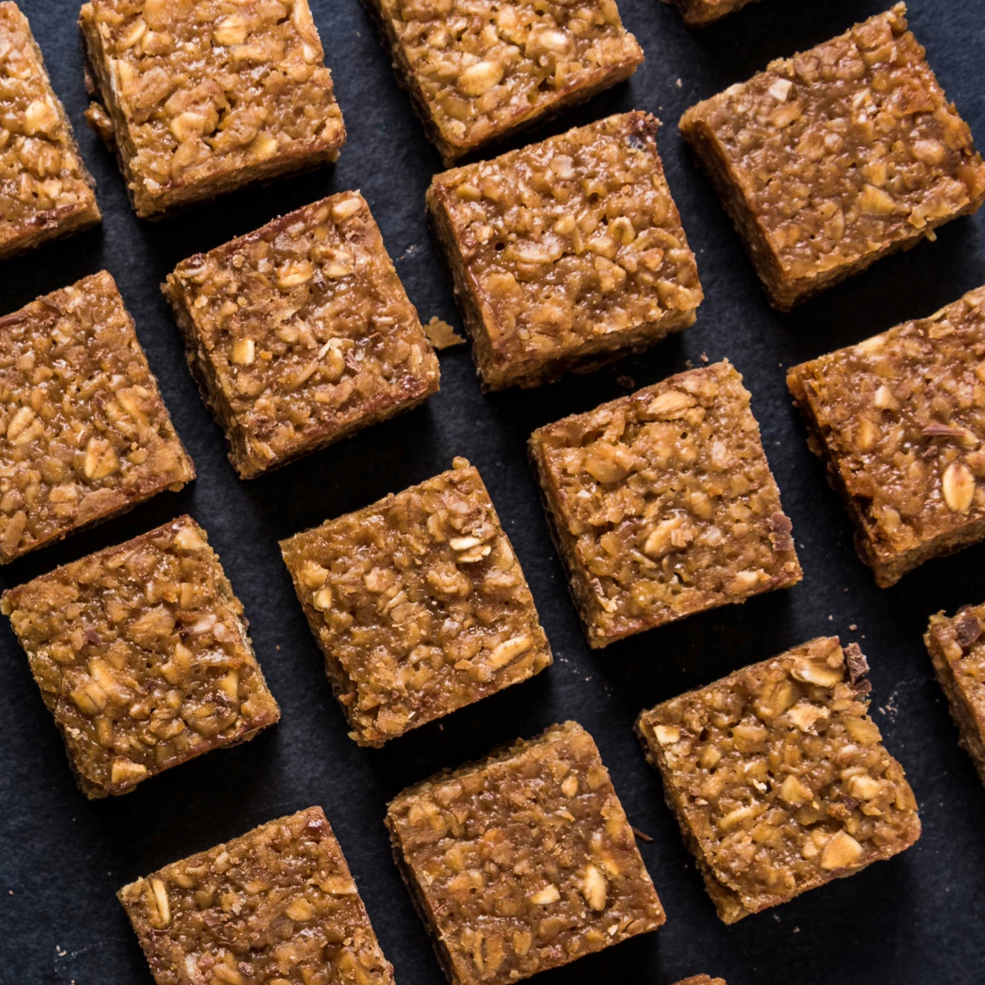 Square granola bars arranged diagonally on a dark background