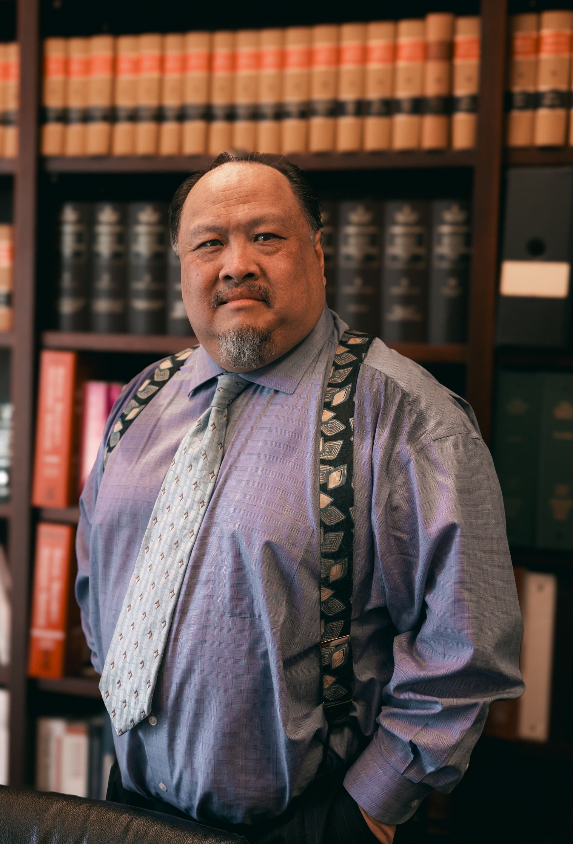 Man wearing tie and suspenders in a law office, bookshelves in the background.