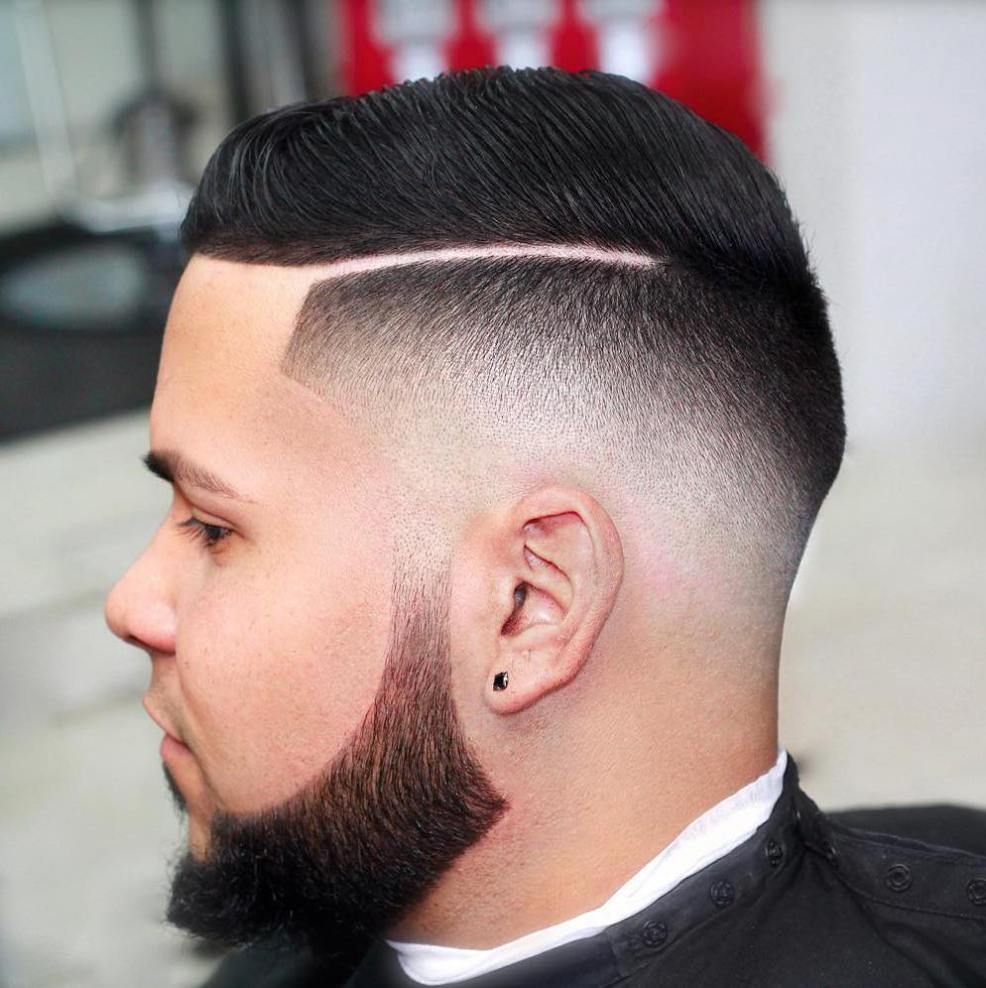 A man with a beard is getting his hair cut at a barber shop.