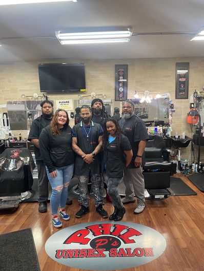 A group of people are posing for a picture in a barber shop.