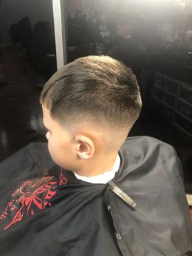 A young boy is getting his hair cut at a barber shop.