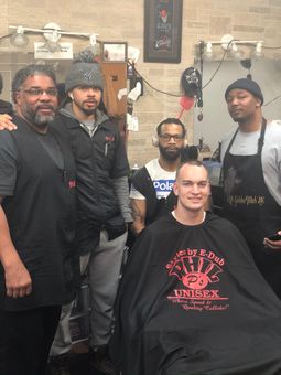 A group of men are posing for a picture in a barber shop.