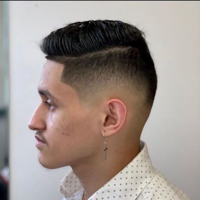 A man wearing a white polka dot shirt has a cross earring.