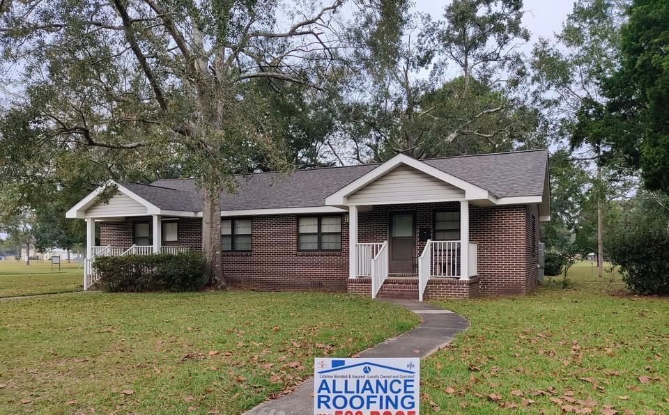 Brick ranch house with a new roof, a walkway, and Alliance Roofing sign in the yard.