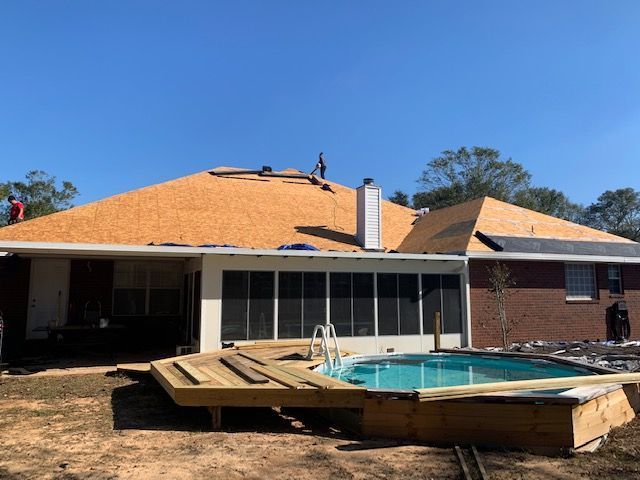 House with new roof under construction; pool and deck visible in foreground.