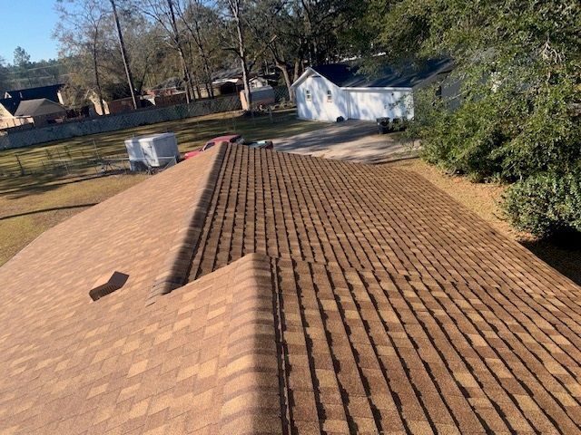 Brown shingled roof of a house on a sunny day.