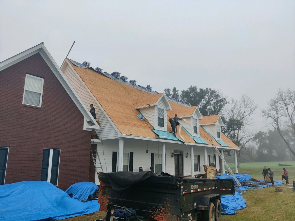 Roofers working on a house with a red side and white side with dormers, cloudy day.
