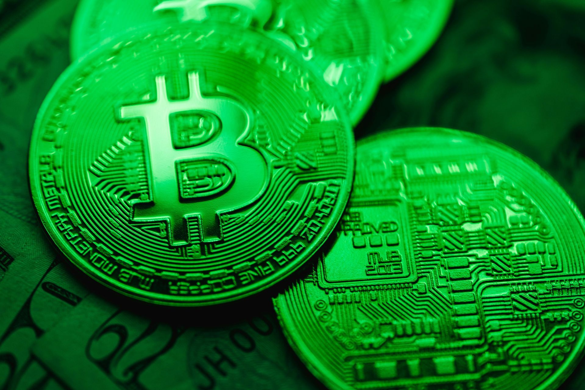 Groen getinte close-up van Bitcoin-munten, opgestapeld op bankbiljetten.