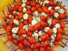 A white plate topped with tomatoes and mozzarella on skewers. A white plate topped with tomatoes and mozzarella on skewers.