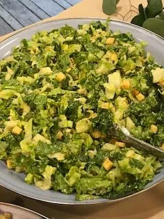 A salad with tomatoes , cucumbers , carrots , onions and lettuce in a bowl with a fork